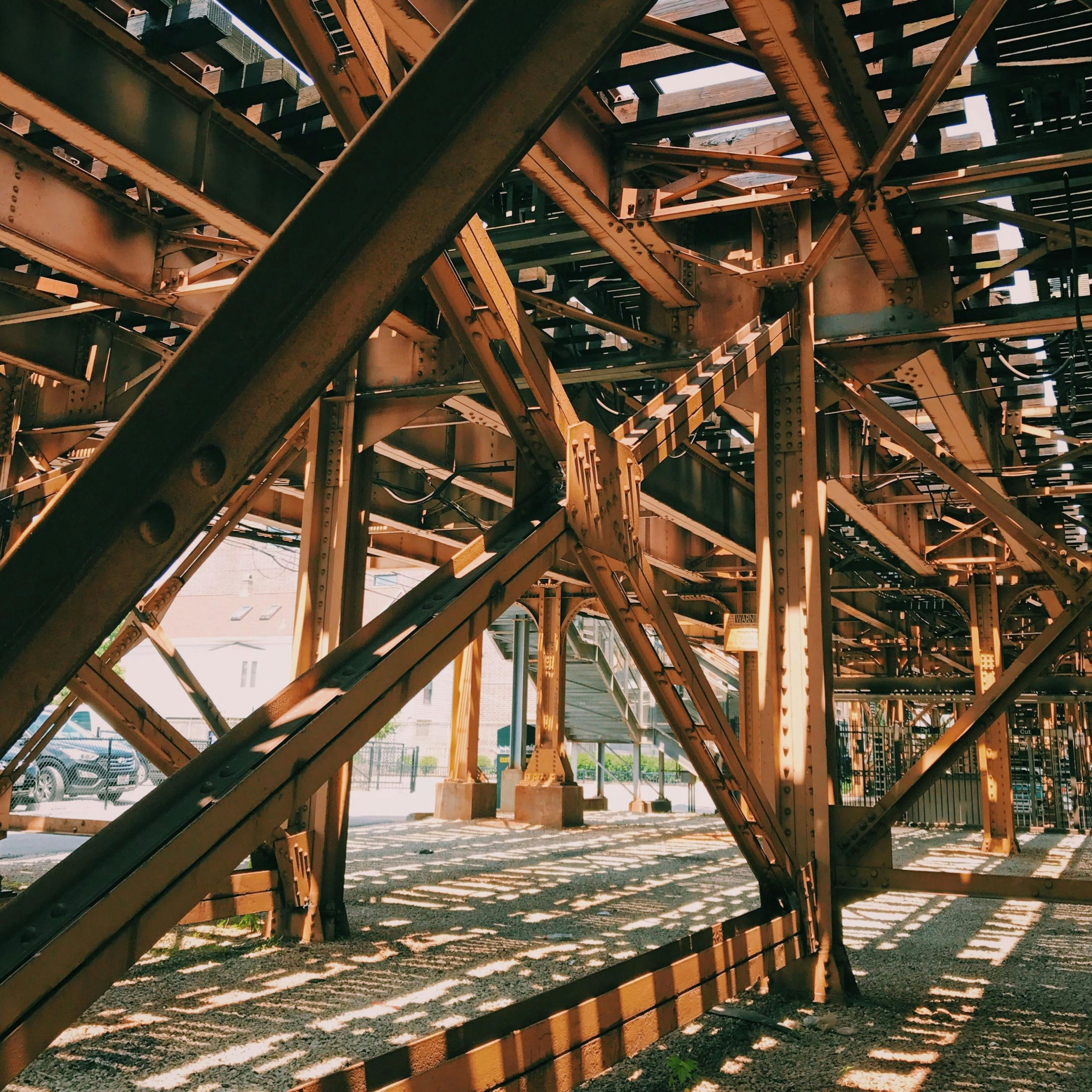 Rusty steel beams form an intricate pattern under a bridge in Chicago.